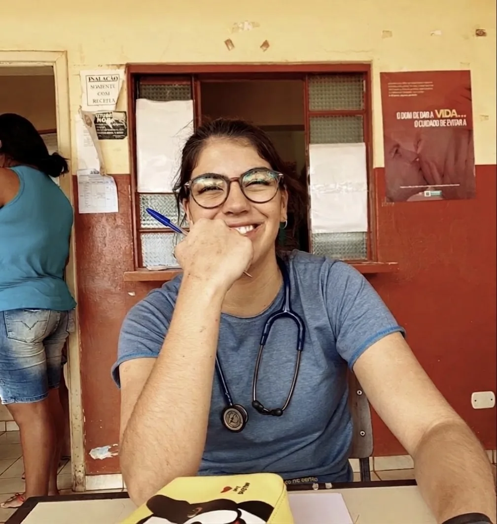 Dra. Luisa sorrindo em ambiente clínico, com estetoscópio